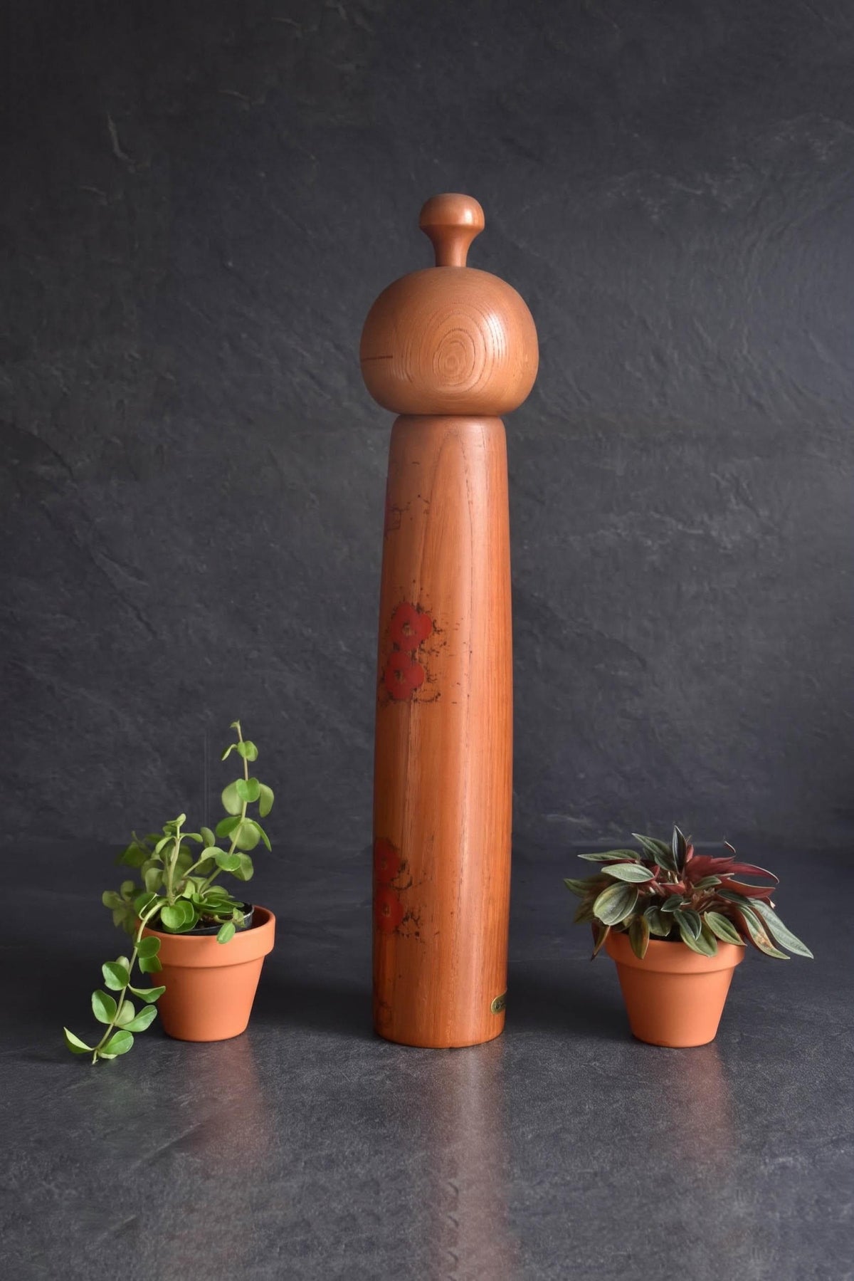 Toa Sekiguchi kokeshi doll standing between two small potted plants