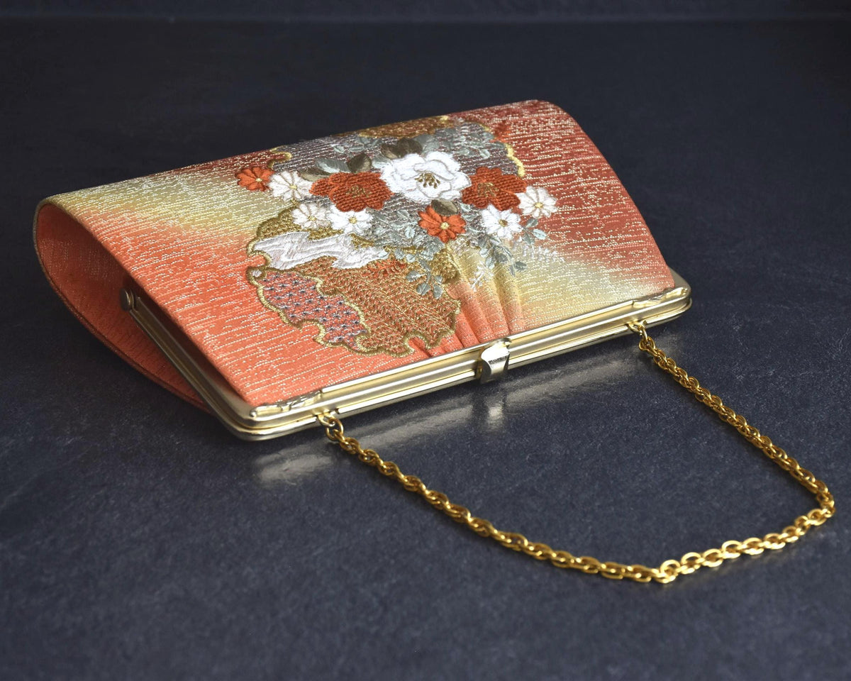 Floral Woven Kimono Clutch angled view resting on a dark surface with chain