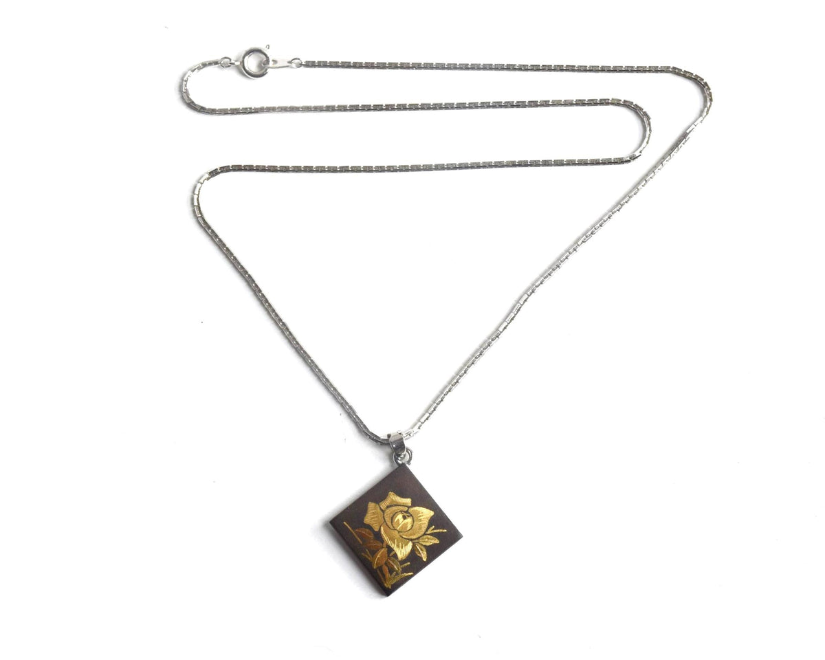 Japanese Zogan Floral Damascene Pendant Necklace laid flat showing the chain and pendant