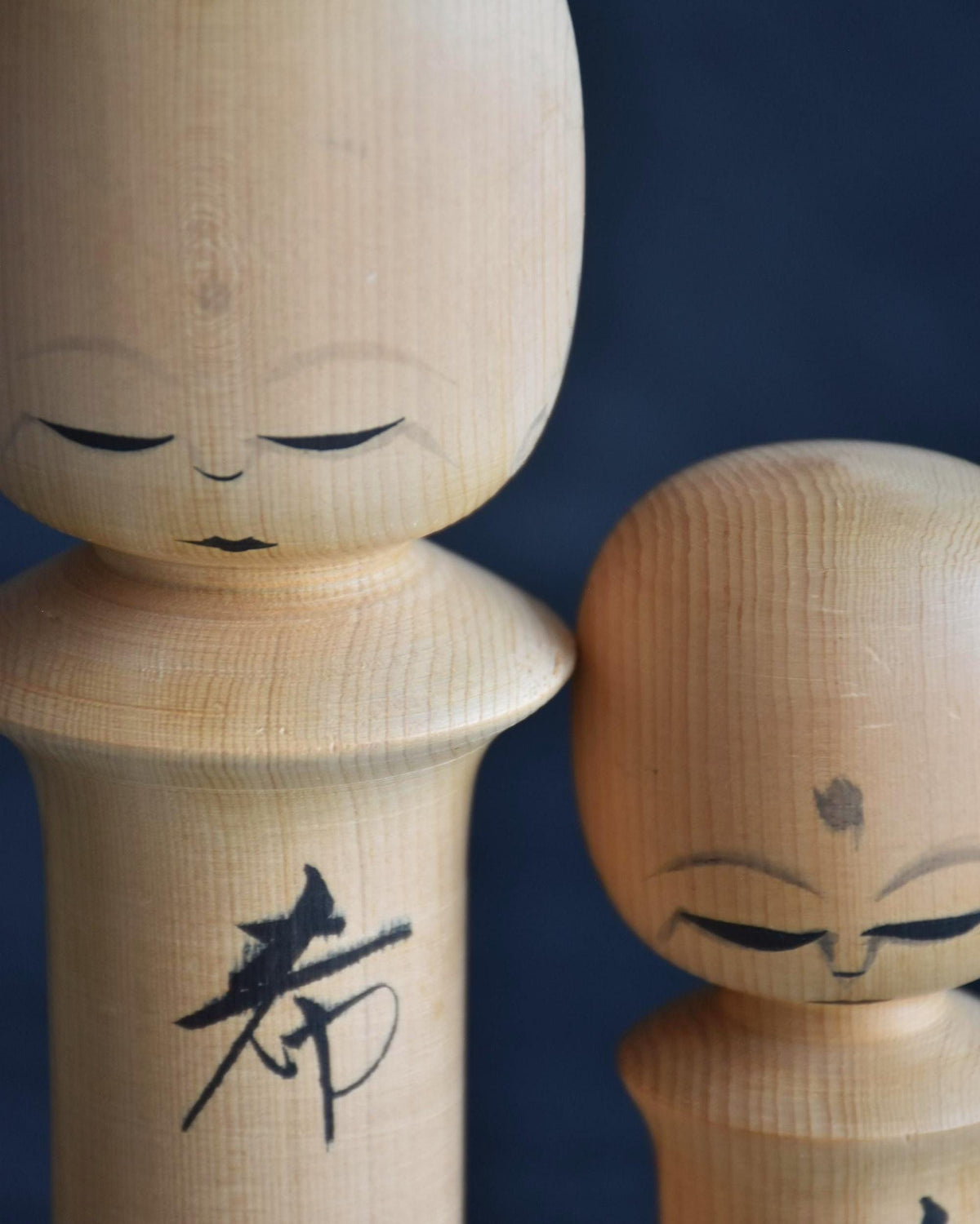 Isamu Ise kokeshi dolls close up of serene painted facial features and kanji.