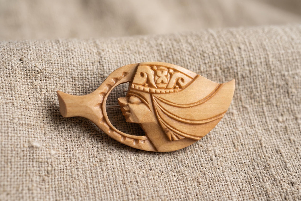 Ainu hand-carved wooden brooch resting on coarse neutral fabric