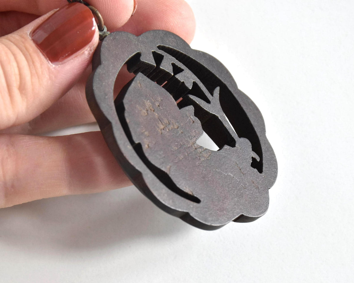 Ainu wooden pendant necklace angled back view highlighting the reverse texture