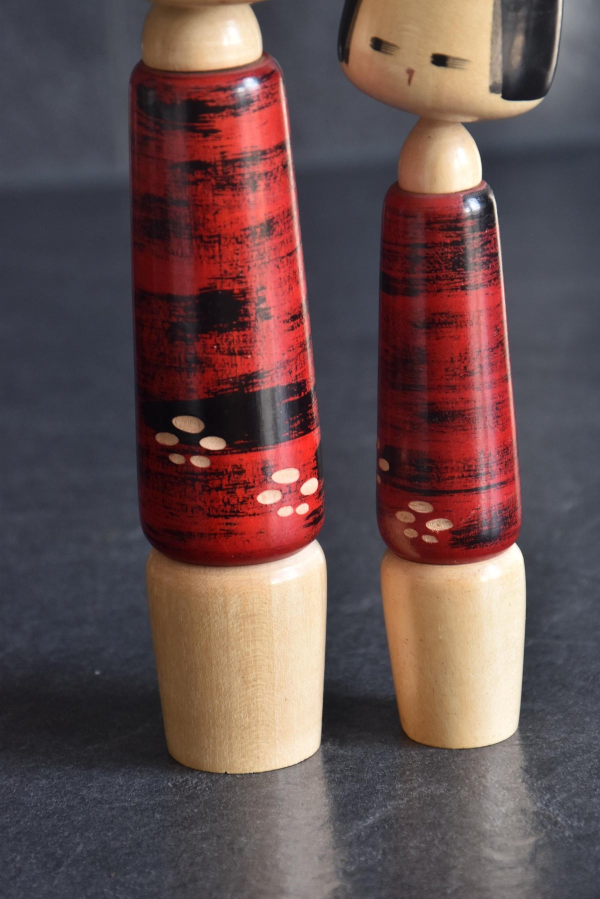 Aida Seihou kokeshi Sisters pattern detail showing the carved white blossom motifs on the red and black kimonos