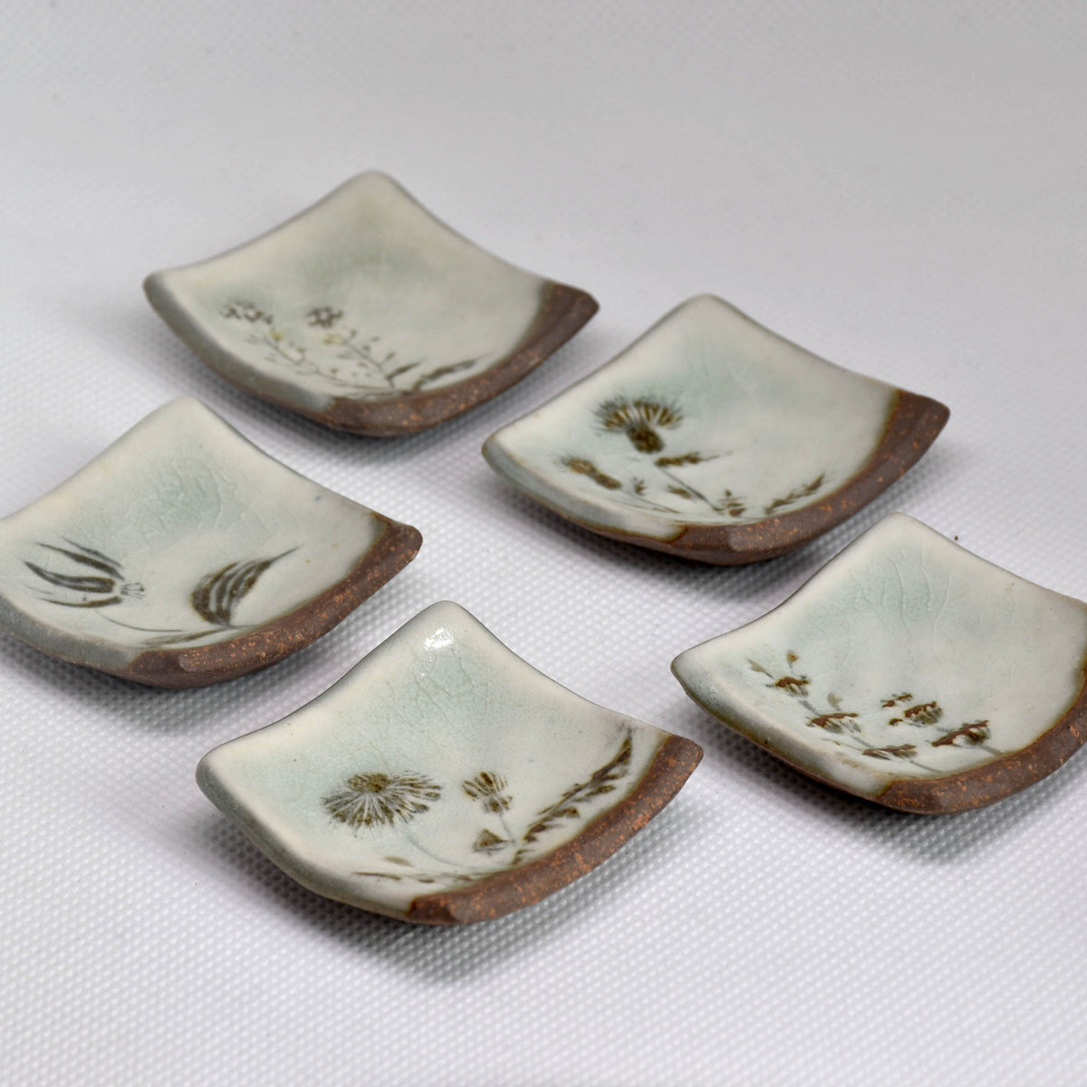 Set of artisan ceramic and wooden Hashioki chopstick rests for authentic Japanese table setting.