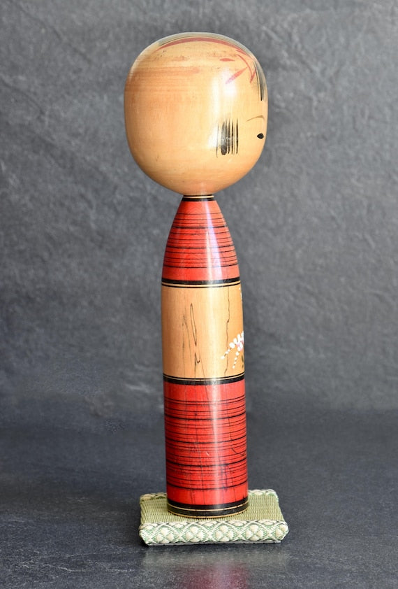 Agatsuma Kichisuke kokeshi side profile view showing the slender wooden form and painted red stripes