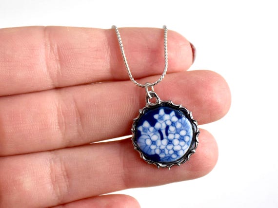 Kiyomizu-yaki Blue Floral Pendant Necklace held in a hand showing the detailed circular bezel