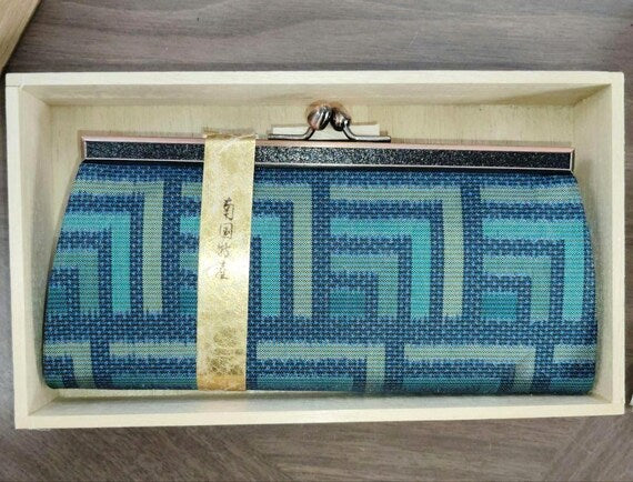 Oshima Tsumugi silk coin purse centered in the wooden box with gold decorative paper band