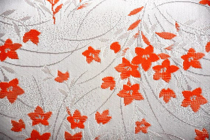 Kimono clutch fabric detail showing woven shimmering orange floral motifs on a soft pearly beige base