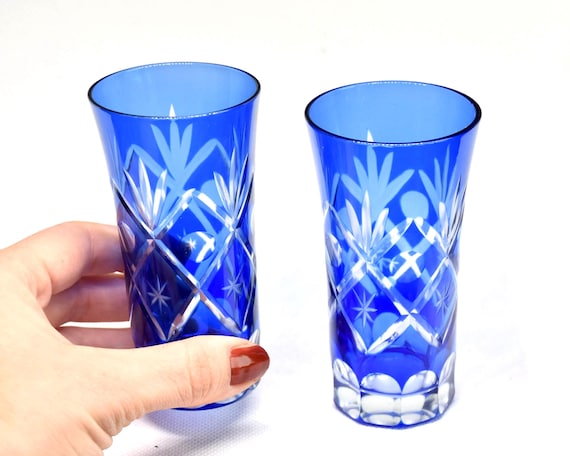 Aisai-Kiriko cut crystal sake cups shown next to a hand for size comparison