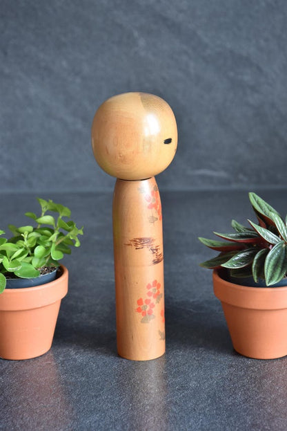 Kokeshi Doll Floral Pattern Japanese wooden doll showing hand-painted red floral pattern