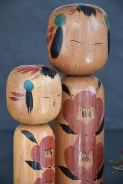 Takahashi Hashime kokeshi pair angled view focusing on the minimalist facial details and hair