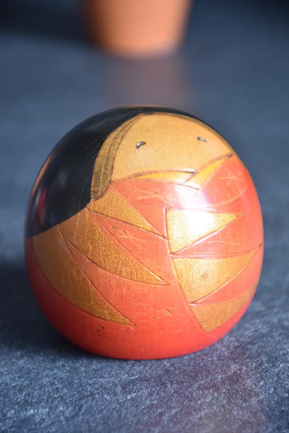 Yamagishi Masayoshi sosaku kokeshi close up of face and geometric carvings on orange