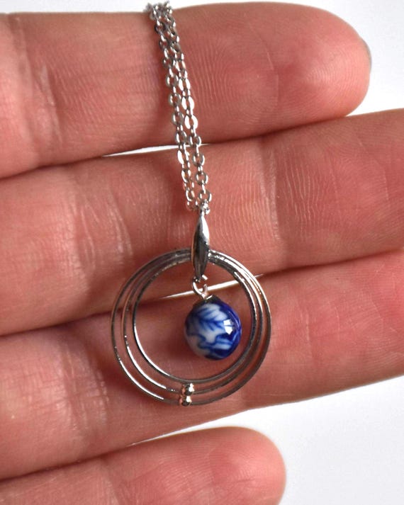 Kiyomizu-yaki Blue Floral Pendant Necklace shown next to a hand for size scale