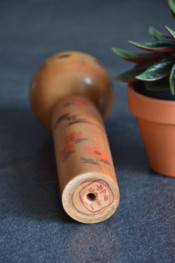 Kokeshi Doll Floral Pattern base of the wooden figurine showing red artist seal signature