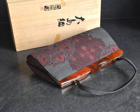 Oshima Tsumugi Kimono Bag angled view showcasing the textured surface next to original paulownia wood box