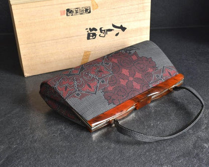 Oshima Tsumugi Kimono Bag angled view showcasing the textured surface next to original paulownia wood box