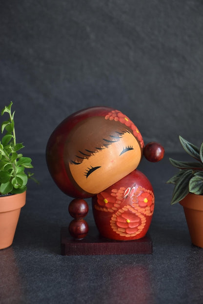 Chie Tamura Pigtail Kokeshi doll with tilted oversized head and red and orange flower painted body