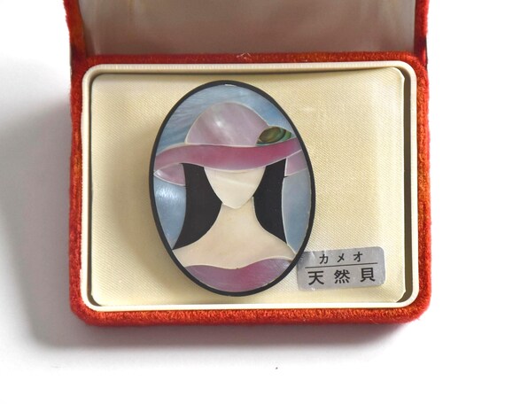 Raden shell inlay brooch resting inside original red presentation box