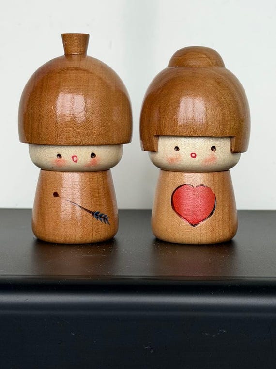 Masashi Takeda kokeshi dolls front view showing the Cupid arrow and pink heart details
