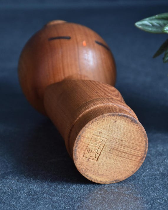 Aida Seihou kokeshi doll base angled to reveal the authentic impressed artist signature stamp