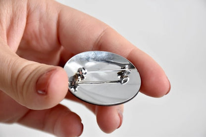Zogan Plum Blossom Brooch showing the polished silver tone back and metal clasp mechanism held in a hand