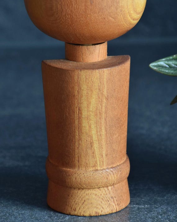 Aida Seihou kokeshi doll back view showing the smooth carved wooden kimono shape and rounded base