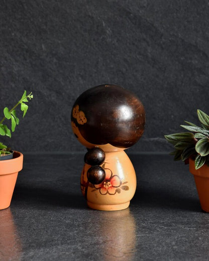 Jiro Tsuda kokeshi doll showing back view of the dark head and floral body pattern
