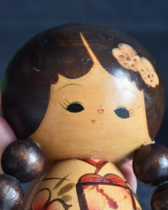 Jiro Tsuda kokeshi doll close-up of the sweetly painted face and wooden pigtails