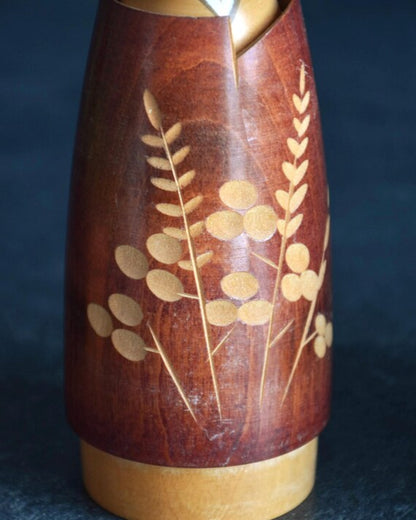 Masae Fujikawa creative kokeshi figurine close up showing the delicate botanical motifs and slender plant stalks