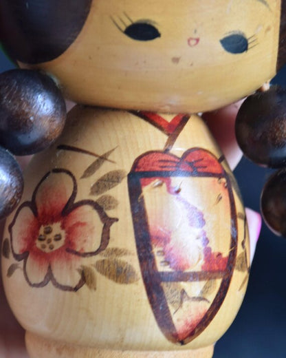 Jiro Tsuda kokeshi doll close-up of the traditional kimono painted with red flowers