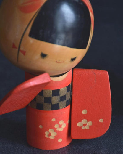 Sansaku Sekiguchi red kokeshi doll pattern detail with floral and checkered motifs
