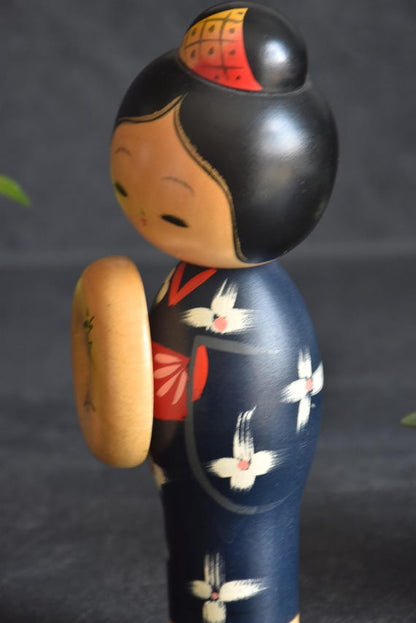 Miyashita Hajime kokeshi doll side profile, showing the red and gold hair piece and kimono detail