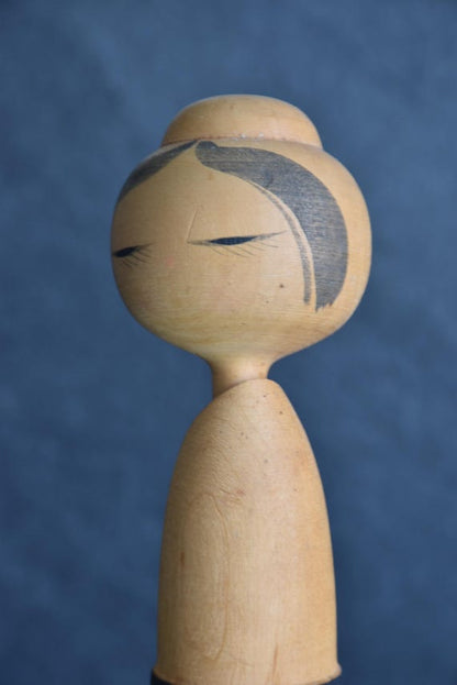 Sato Suigai kokeshi facial detail showing closed painted eyes and hair brushstrokes