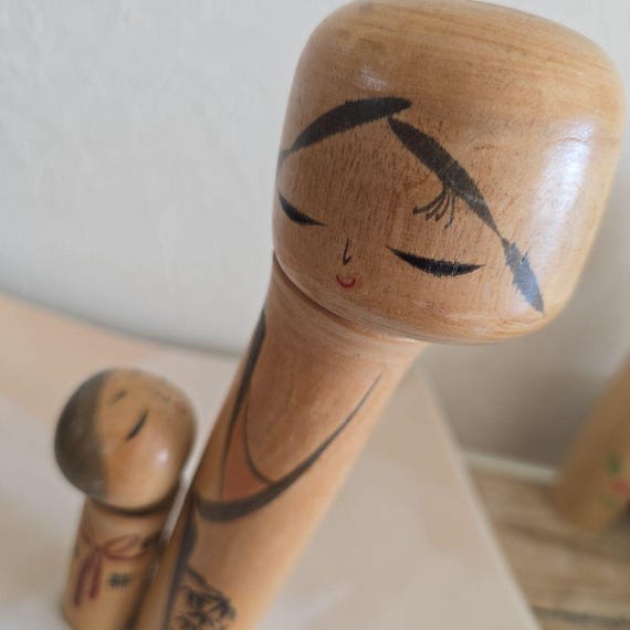 Oshin Kokeshi by Sato Suigai close-up of the mother figure's painted face and hair details.