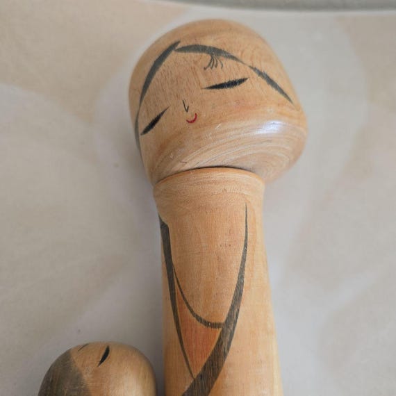 Oshin Kokeshi by Sato Suigai close-up of the mother figure's face looking down at child.