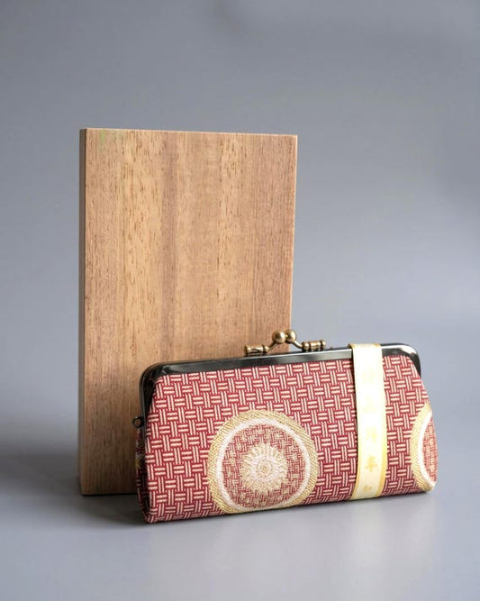 Nishijin-Ori Silk Brocade Coin Purse in red silk brocade with geometric pattern next to a wooden box
