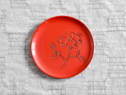 Murakami Kibori Tsuishu Camellia Red Lacquer Plate displayed flat on a grey fabric background