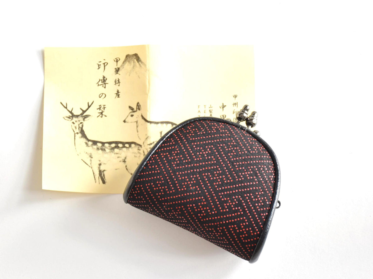 Inden deerskin coin purse displayed next to its traditional informational booklet