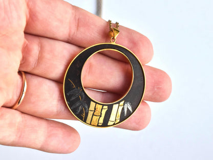 Amita Damascene Pendant Necklace Bamboo Grove shown next to a hand for scale