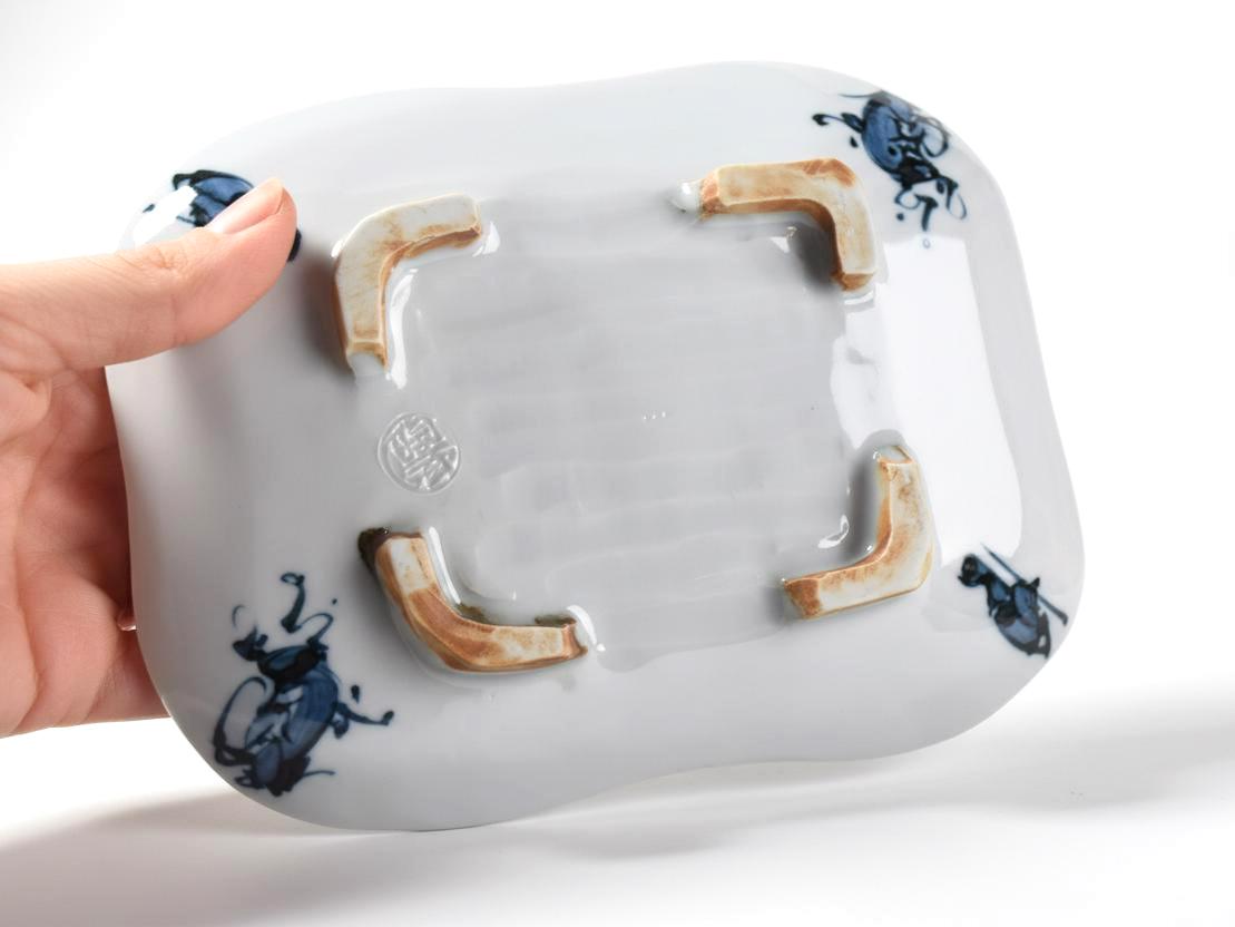 Tōsai Kiyomizu-yaki porcelain plate base held by hand showing the impressed maker seal