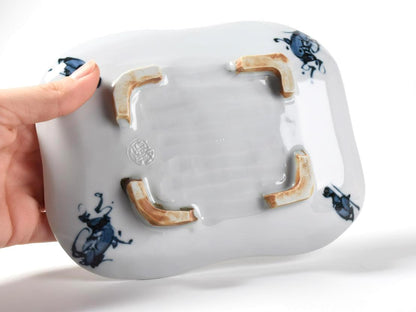 Tōsai Kiyomizu-yaki porcelain plate base held by hand showing the impressed maker seal
