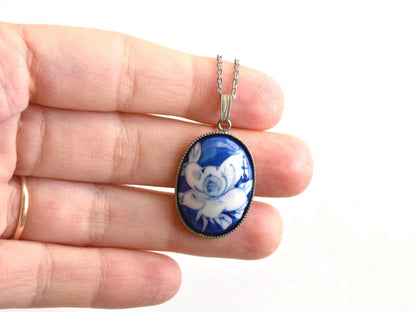 Japanese Cobalt Blue Floral Porcelain Pendant Necklace shown next to a hand for scale