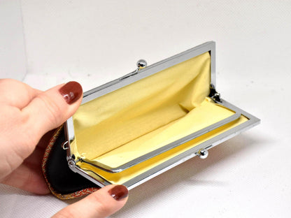 Saga Nishiki coin purse opened wide to reveal the yellow interior lining held in a hand