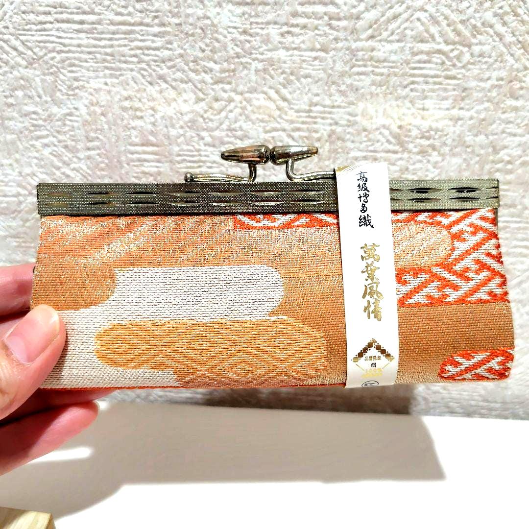 Hakata-Ori Silk Gamaguchi Coin Purse held in a hand to demonstrate the scale and proportions of the accessory.