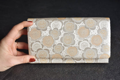 Nishijin-Ori silk clutch held in hand displaying scale and angle against dark surface