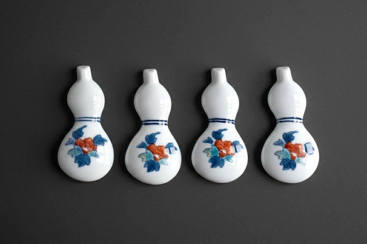 Porcelain gourd chopstick rests set of four arranged in a row on a dark grey surface