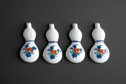 Porcelain gourd chopstick rests set of four arranged in a row on a dark grey surface