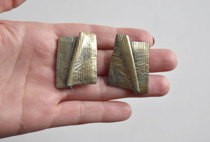Matching clip-on earrings from the sculptural leather jewelry set shown in hand