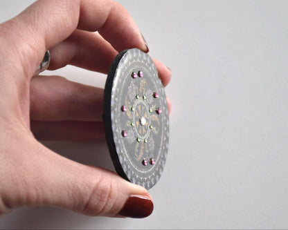 Japanese lacquerware floral brooch held sideways showcasing the raised elements