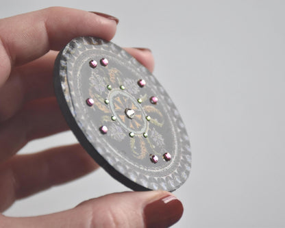 Japanese lacquerware floral brooch tilted to show surface texture and bead accents
